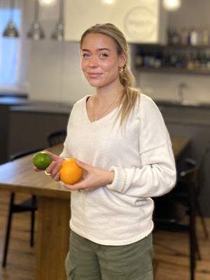 Mitarbeiterin mit einer Orange und Limette in den Händen
